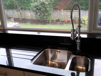 Absolute black granite worktops showing under mounted sink and drainage grooves.Black kitchen worktops Lightwater Surrey